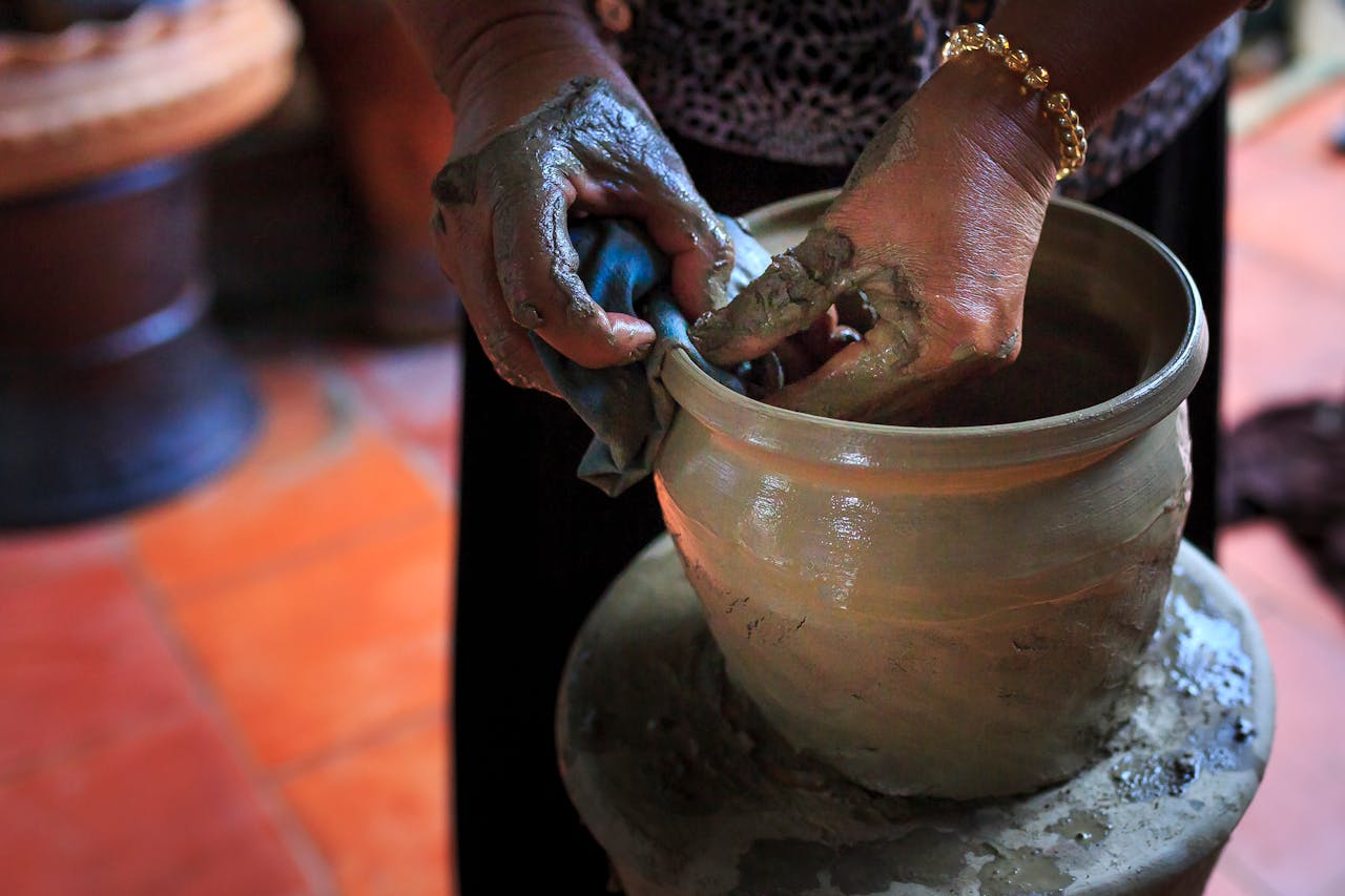 Close-up of hands shaping a clay pot on a wheel, showcasing traditional pottery craftsmanship.